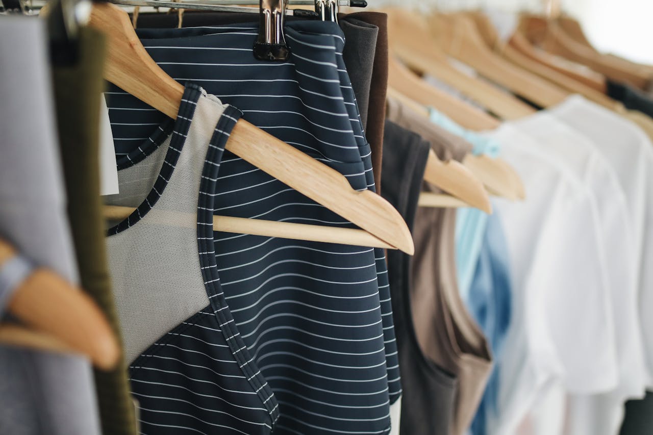 A close-up view of various clothing items hanging on wooden hangers in a retail store.