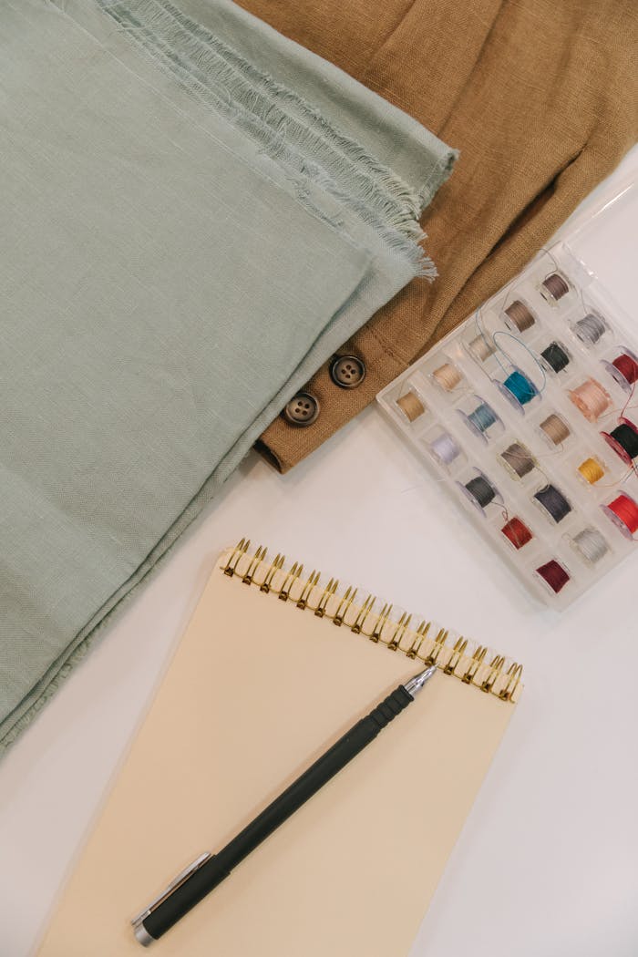 Flat lay of sewing materials and notebook for creative planning.